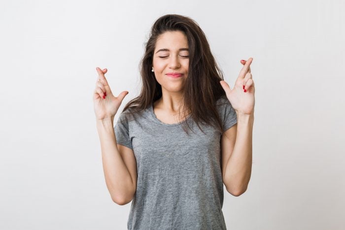 Woman crossing fingers, one of the hand signs with different meaning