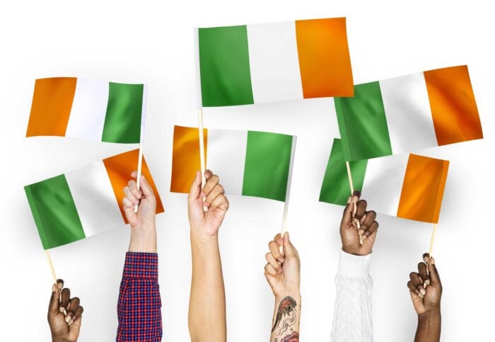 Diverse hands waving Irish flags to celebrate the Irish language