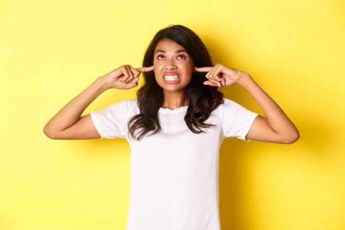 Annoyed woman covering her ears and using the Korean slang word for "shut up".