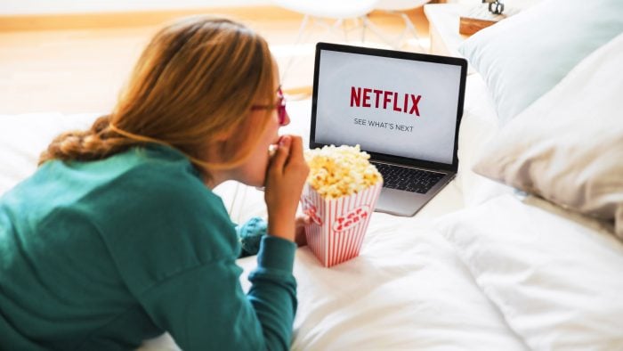 Woman watching french films on netflix and eating popcorn