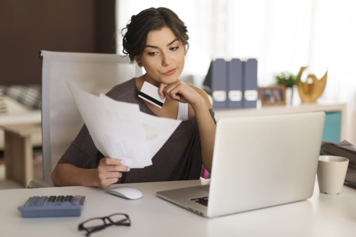 Woman holding a credit card and paying her bills online to exemplify one of the French idioms