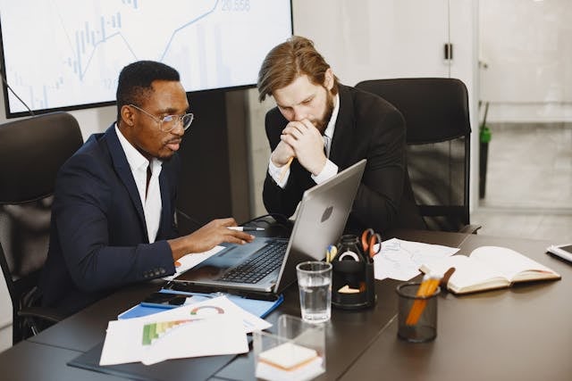 Two men looking at a computer screen in a business meeting