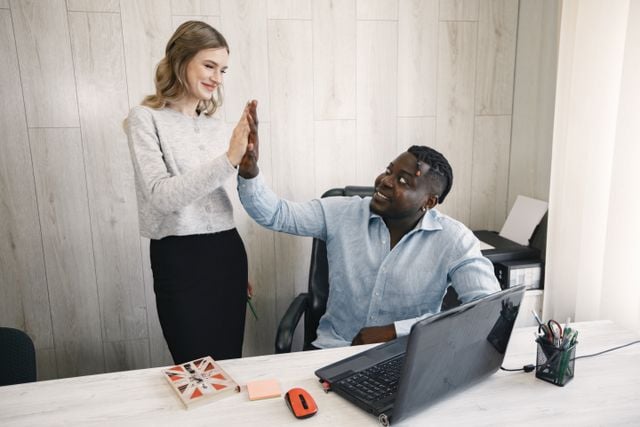 Colleagues celebrating an achievement with a high five in a German workplace.