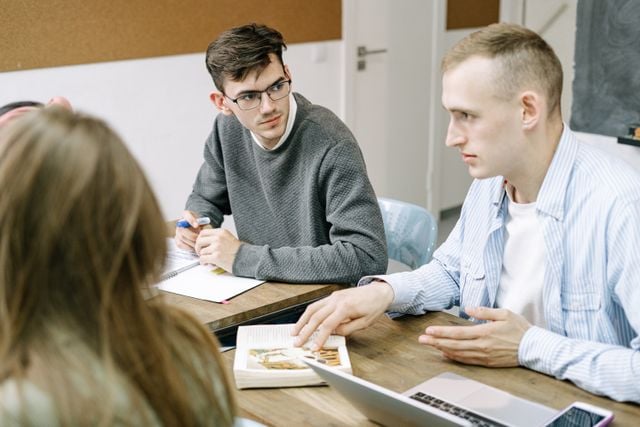 German learners discussing a textbook in a classroom.
