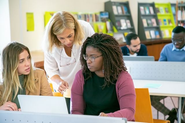Two adult language learners and their teacher in class.