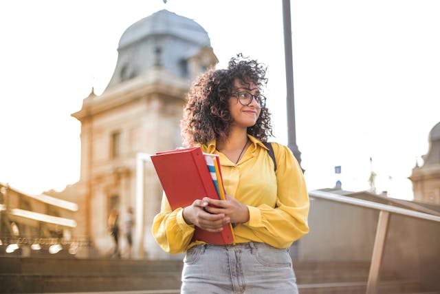 Young woman carrying a book and a folder.