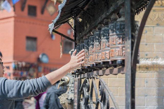 Visitor turning Buddhist prayer wheels at a temple in Nepal.