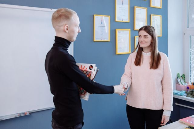 Language learner shaking hands with a teacher, highlighting how second-language skills can support career opportunities.